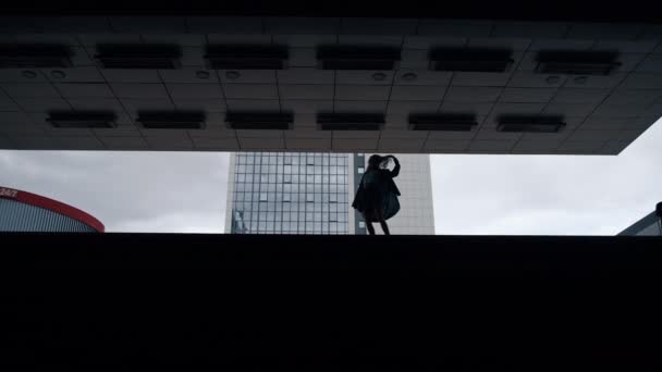 Silhouet vrouw wandelen parkeerplaats donker gebouw in de stad buiten. — Stockvideo