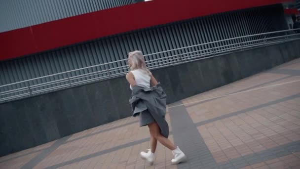 Podekscytowana kobieta pozowanie zdjęcie w miejskim stroju w architekturze miasta. — Wideo stockowe