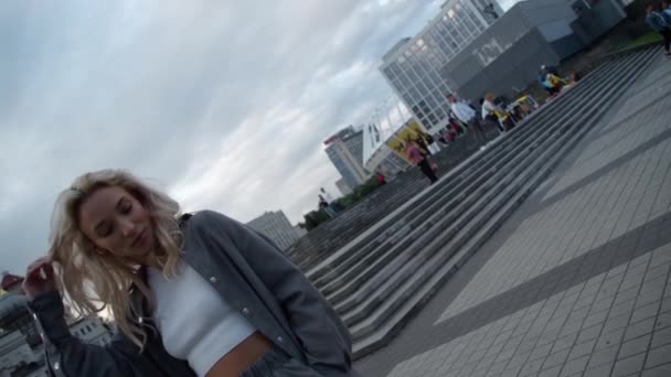 Mujer alegre tocando el pelo en los edificios modernos de la ciudad calle. — Vídeos de Stock