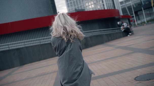 Fille excitée marchant au centre-ville touchant les cheveux près des bâtiments urbains. — Video