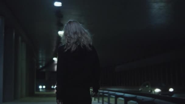 Kvinnlig person natt promenad på motorvägen bär urbana kläder i körtunneln. — Stockvideo