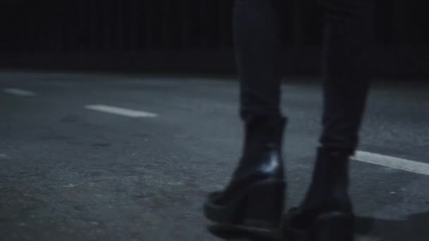 Жіночі ноги, що йдуть шосе в чорному взутті або темній дорозі з проїжджаючими машинами . — стокове відео