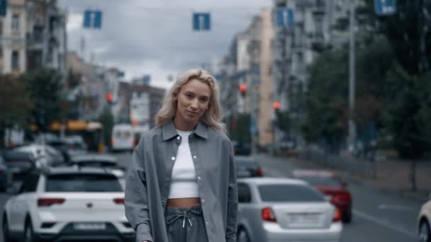 Mooie vrouw neemt wandeling in stadsgezicht in de buurt van weg met rijdende auto 's. — Stockvideo