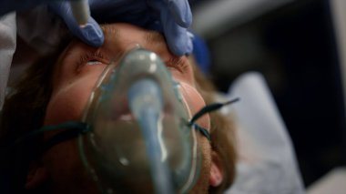 Paramedikler el feneriyle adamı kontrol ediyor. Doktor erkek hastayı muayene ediyor. 