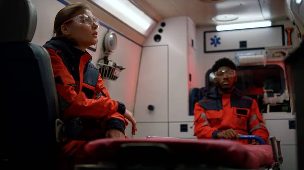 Operai del pronto soccorso seduti su un veicolo di emergenza. Personale medico di guardia — Foto Stock
