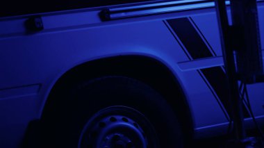 Amblemli ambulans arabası. Karanlıkta kırmızı ve mavi ışıklar yanıp sönüyor.
