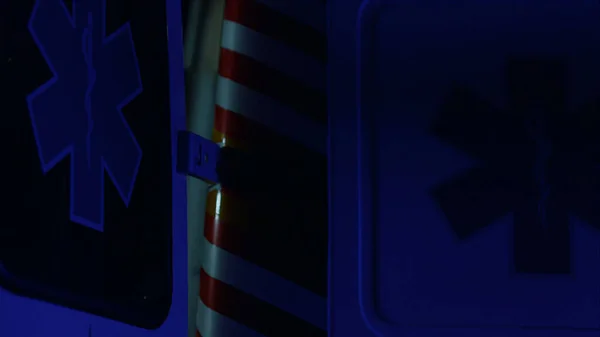 Blått och rött nödljus blinkar i mörker. Ambulansbil parkerad på gatan — Stockfoto