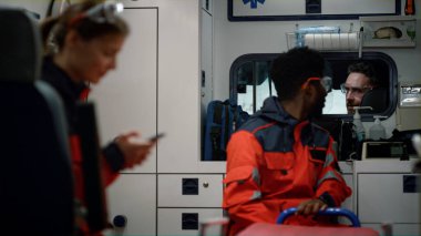 Doktorlar acil durum arabasıyla kurtarma için acele ediyorlar. Sağlık görevlileri araçta oturuyorlar.