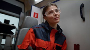 Gülümseyen profesyonel sağlık görevlisi acil durum arabasında meslektaşıyla iş tartışıyor.