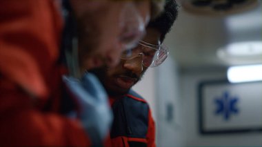 Acil servis doktoru steteskopu çıkarıyor. Sağlık görevlileri gece vardiyasında çalışıyor. 