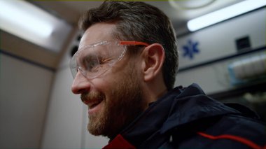 Gülümseyen ambulans sağlık görevlisi acil durum arabasında meslektaşıyla konuşuyor.