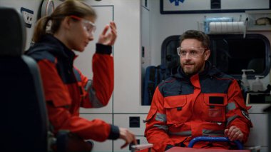 Ambulans arabasında acil tıbbi servis ekibi konuşuyor. Doktor başını sallıyor.