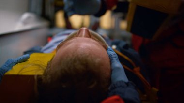 Kapalı tıbbi çalışanlar ambulans arabasındaki hastalarla ilgileniyorlar.