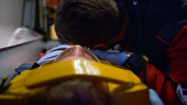 Eldivenli ambulans ambulans ambulans arabasındaki sedyelerle hastayı muayene ediyor.