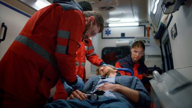 Doktorlar ambulans arabasında sedyeyle kurbanla ilgileniyorlar.