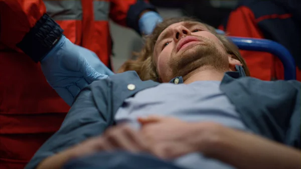 Człowiek leżący na noszach w samochodzie pierwszej pomocy. Mężczyzna odczuwa ból brzucha — Zdjęcie stockowe