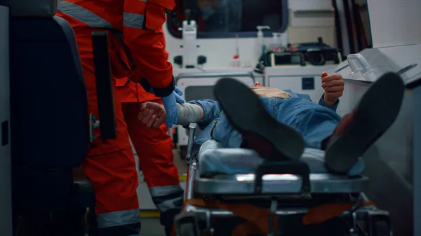 Paramédicos provando primeiros socorros ao paciente. Médicos aplicando bandagem na mão do homem — Fotografia de Stock