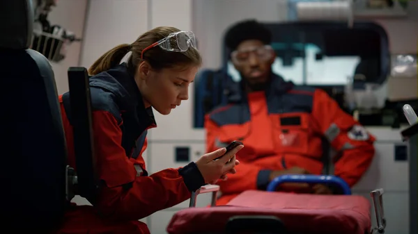 Paramedici in corso in un incidente d'auto in ambulanza. Medico utilizzando smartphone — Foto Stock