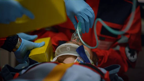 Paramedici zorgen voor eerste hulp voor de mens. Artsen met zuurstofmasker op slachtoffer — Stockfoto