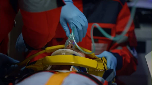 Médicos de emergência fornecendo ajuda médica para o paciente em máscara de oxigênio — Fotografia de Stock