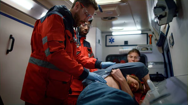 Asistente de atención de emergencia que proporciona ayuda médica al paciente en el coche de ambulancia —  Fotos de Stock