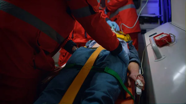 Paramedics giving first aid to patient in ambulance car. Doctor examining man — Stock Photo, Image