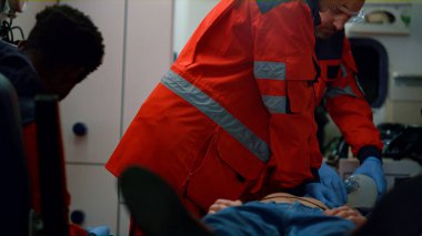 Karışık yarış sağlık görevlileri ambulans arabasındaki hastaya kalp masajı yapıyor.