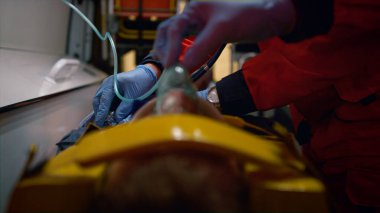 Sağlık görevlileri acil durum arabasında kurban kurtarıyor. Tıbbi asistanlar adamı inceliyor. 