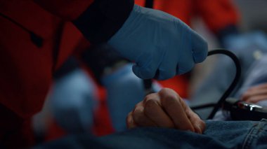 Eldivenli sağlık görevlileri hastanın tansiyonunu tonometreyle ölçüyor.