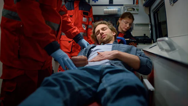 Assistentes de emergência examinando paciente em carro de ambulância — Fotografia de Stock