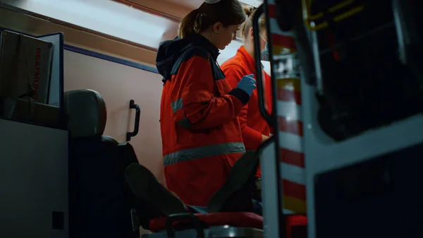 Los paramédicos rescatan al paciente en el coche de emergencia. Médicos tratando al hombre en camillas — Foto de Stock