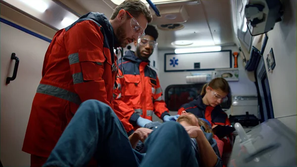 Équipe médicale de course mixte donnant les premiers secours dans la voiture d'ambulance — Photo