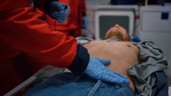 Ratownicy medyczni ratują pacjenta w karetce. Lekarze stosujący holter monitor na człowieku — Zdjęcie stockowe