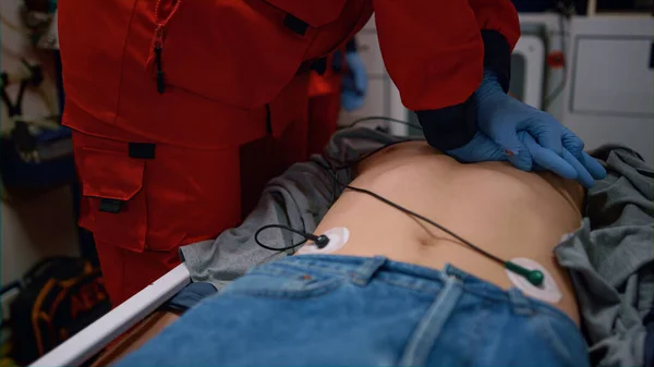 Парамедики делают искусственное дыхание раненого человека на носилках в машине скорой помощи — стоковое фото