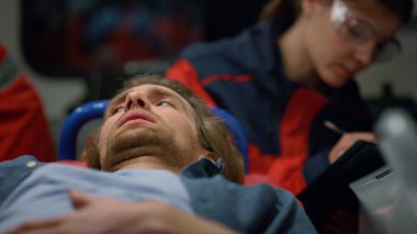 Hasta acil durum aracında sedyelerin üzerinde yatıyor. Karnı ağrıyan bir adam.