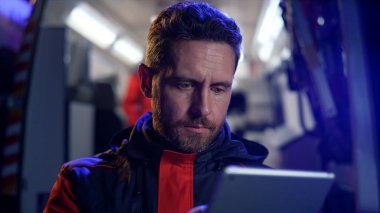 Paramedikler tablet üzerinde çalışıyor. İnternet 'te bilgi okuyan adam