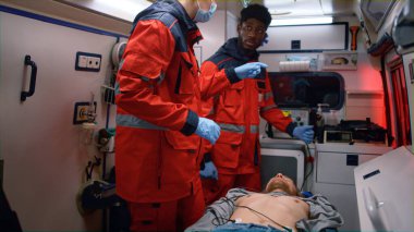 Çok ırklı sağlık görevlileri acil durum arabasındaki adama ilk yardım yapıyor.