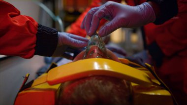 Eldivenli sağlık ekibi ambulans arabasındaki hastaya ilk yardım yapıyor.