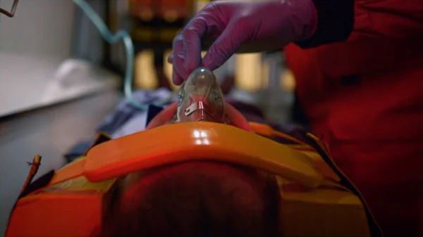 Mano paramedica in guanto con maschera di ossigeno sul viso del paziente in auto di emergenza — Foto Stock