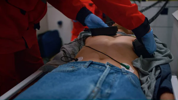 Ratownicy medyczni robią reanimację z defibrylatorem na człowieku w samochodzie. — Zdjęcie stockowe