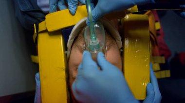 Doktorlar hastaların hayatını kurtarıyor. Sağlık görevlileri adamın kafasını hareketsiz hale getiriyor.