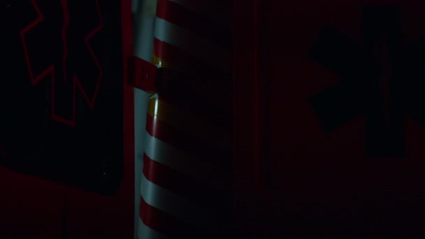 Blauwe en rode noodlichten knipperen in het donker. Ambulance auto geparkeerd op straat — Stockvideo