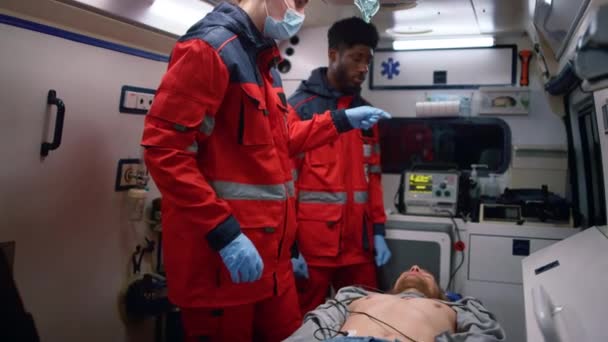 Paramédicos multiétnicos que dan primeros auxilios al hombre en un coche de emergencia — Vídeos de Stock
