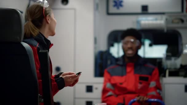 Sorridente medico paramedico che parla con operatore medico afro in auto di emergenza — Video Stock