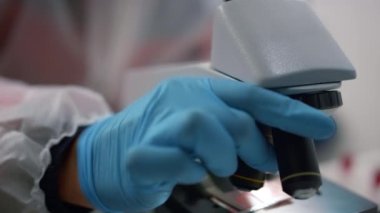 Laboratuvarda mikroskop kullanan bir bilim adamı. Örnekler üzerinde çalışan araştırmacı 