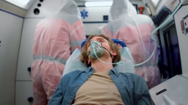 Un hombre sentado en camillas en un vehículo de emergencia. Víctima respirando máscara de oxígeno — Vídeos de Stock
