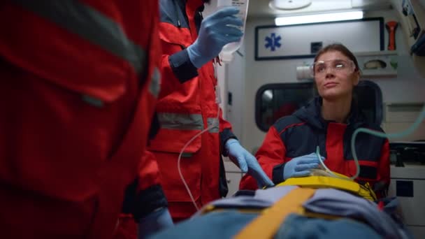 Врачи скорой помощи, оказывающие первую помощь пациенту в машине скорой помощи — стоковое видео