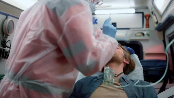 Equipo de paramédicos haciendo una prueba de hisopo nasal en el coronavirus del hombre en el coche de emergencia — Vídeos de Stock