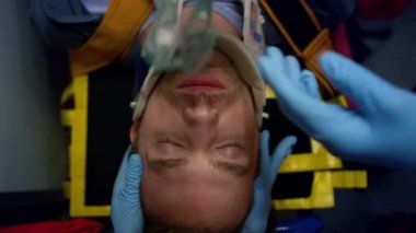 Sağlık görevlisi hastaya oksijen maskesi takıyor. Doktorlar ilk yardım yapıyor.