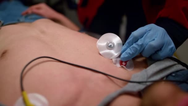 Mãos de médico de emergência aplicando sensores para medir o ECG do homem — Vídeo de Stock